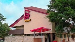 A Red Roof Plus hotel with a stone facade, a red awning, and a covered outdoor seating area. - Red Roof Inn PLUS+ Philadelphia Airport (Essington)