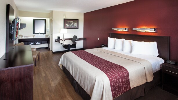 A hotel room with a bed, desk, chair, and a television. - Red Roof Inn PLUS+ Philadelphia Airport (Essington)