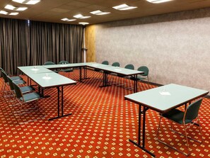 A conference room with a red patterned carpet, multiple tables, chairs, and a curtain backdrop. - ibis Douala (Douala)