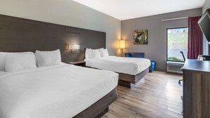 A hotel room with two beds, a desk, a chair, a TV, and a window with curtains. - Clarion Inn near Lookout Mountain (Chattanooga)