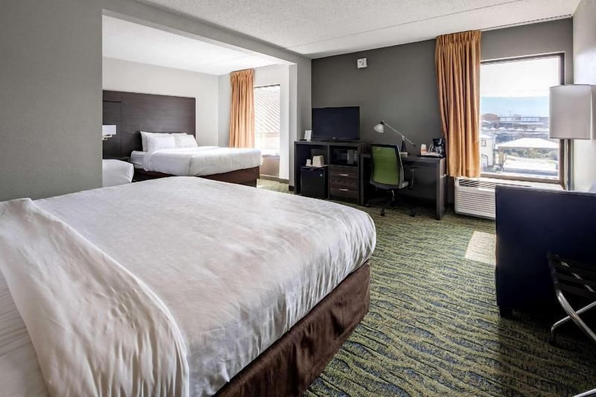 A hotel room with a large bed, a desk, a chair, and a television.
