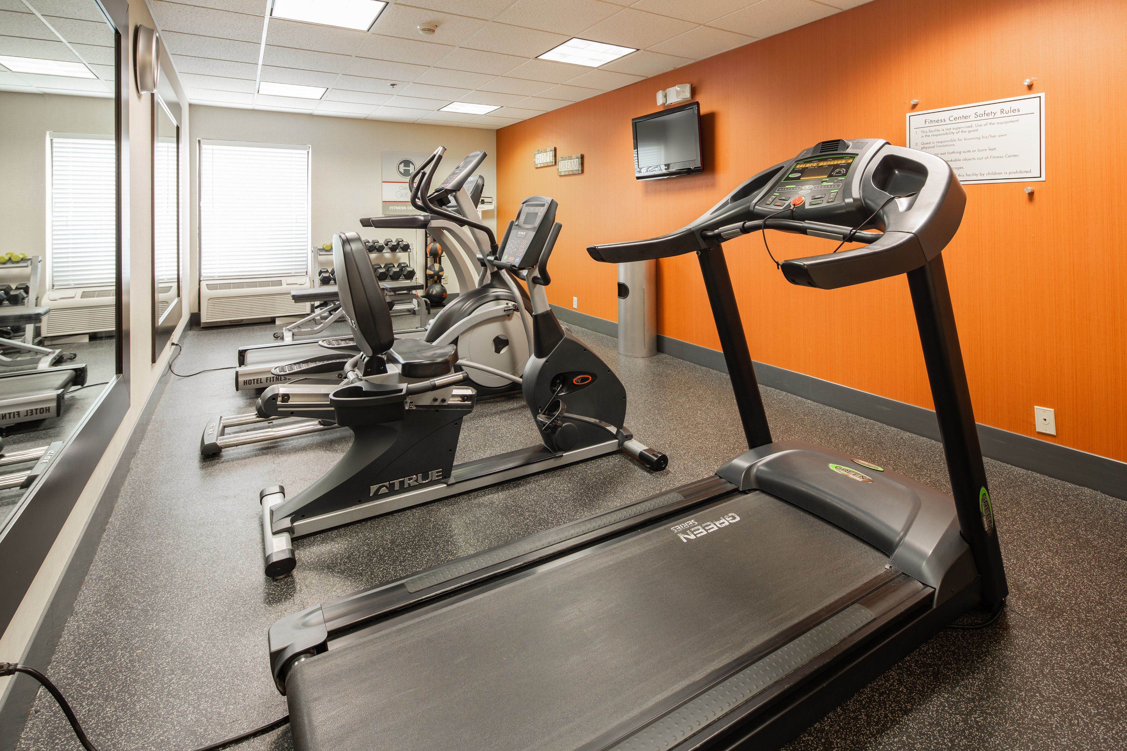 Un gimnasio con cintas de correr, elípticas y máquinas de pesas.