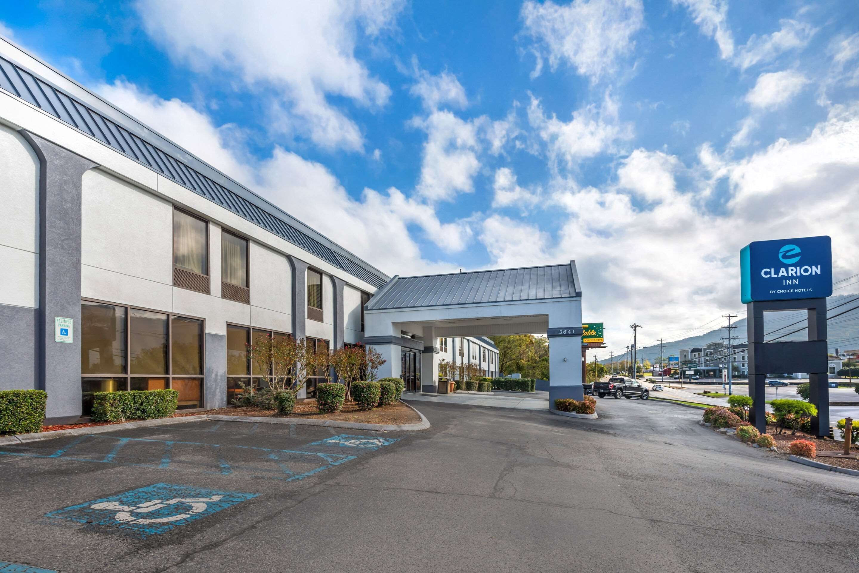 A modern hotel entrance with a parking lot, a covered walkway, and a sign for Clarion Inn by Choice Hotels.