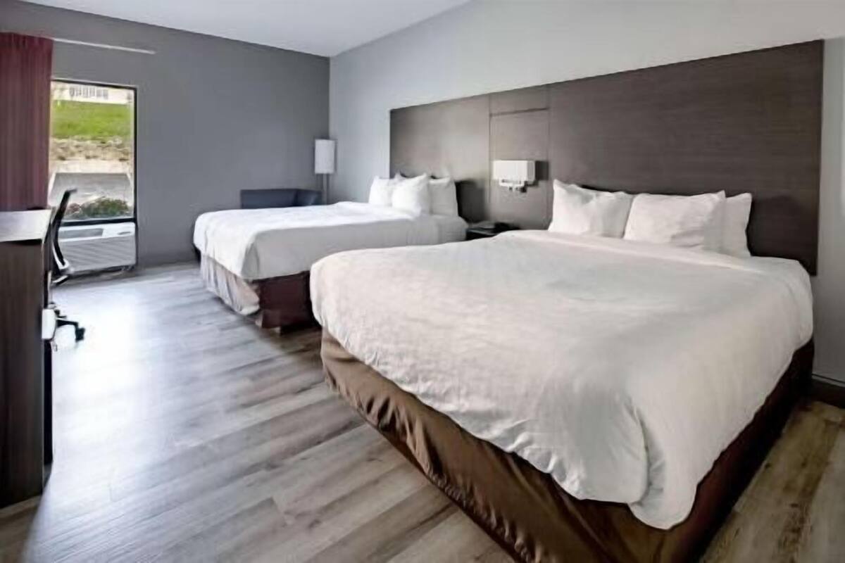 Hotellihuone, jossa on kaksi sänkyä, työpöytä ja ikkuna.