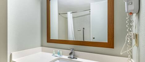 A bathroom with a white sink, a mirror with a wooden frame, and a hairdryer mounted on the wall.