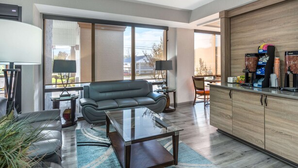 A modern living room with a sofa, coffee table, and a kitchen area with a counter and appliances. - Clarion Inn near Lookout Mountain (Chattanooga)