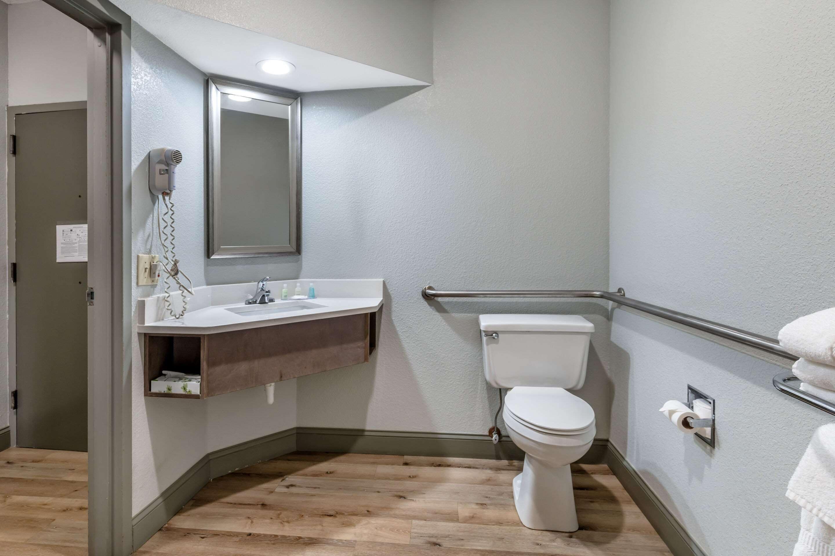 Une salle de bain équipée de toilettes, d’un lavabo, d’un miroir et d’un sèche-mains.