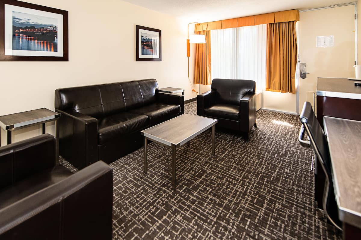 A hotel room with a sofa, armchair, and a small table.
