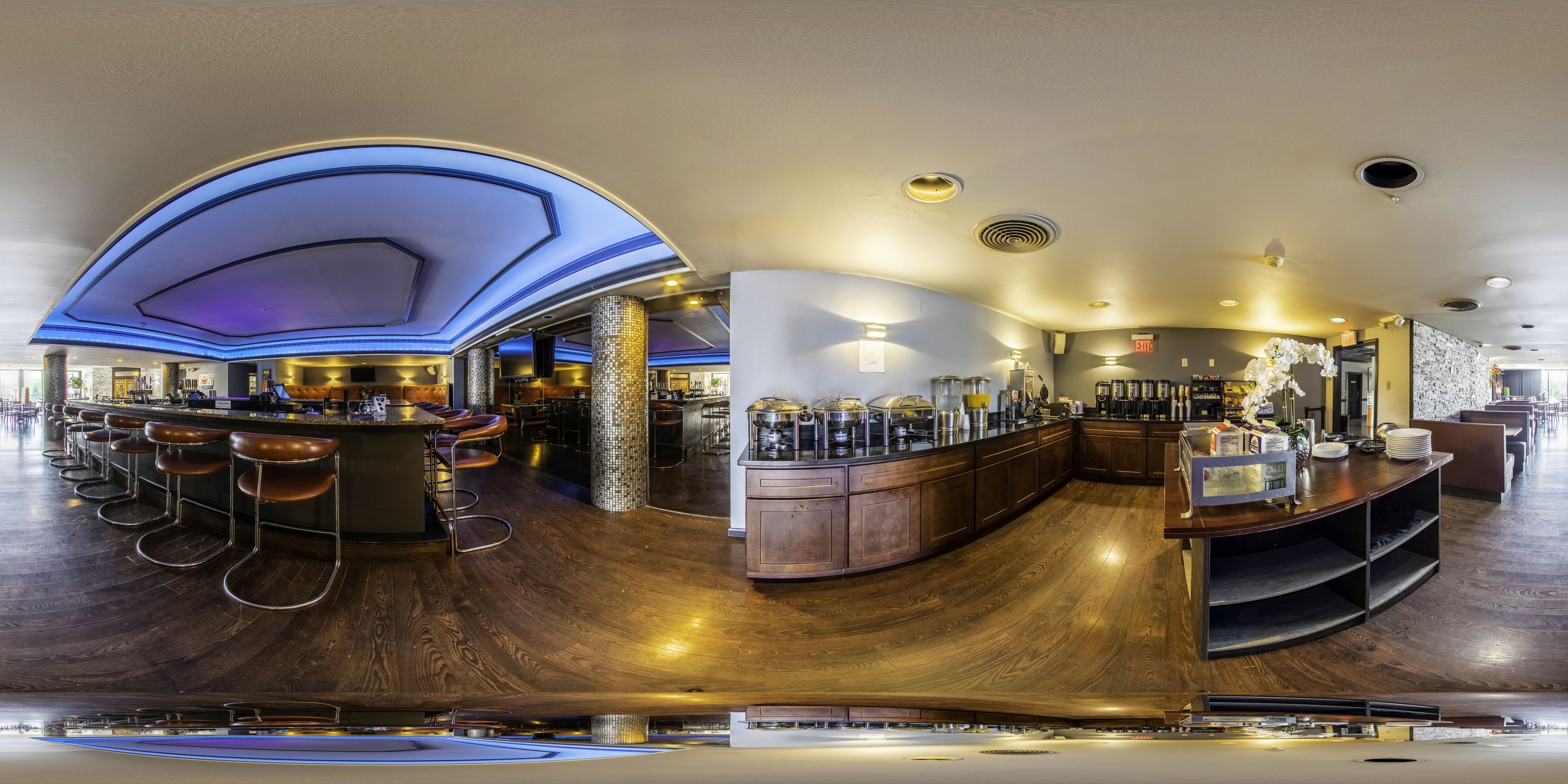 A modern bar area with a curved wooden counter, bar stools, and a decorative ceiling.