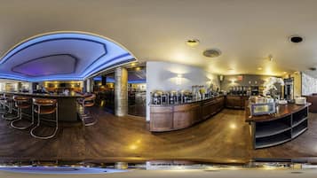 Uma área de bar moderna com um balcão de madeira curvo, banquetas e um teto decorativo.