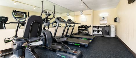 A gym with treadmills, elliptical machines, and dumbbells.