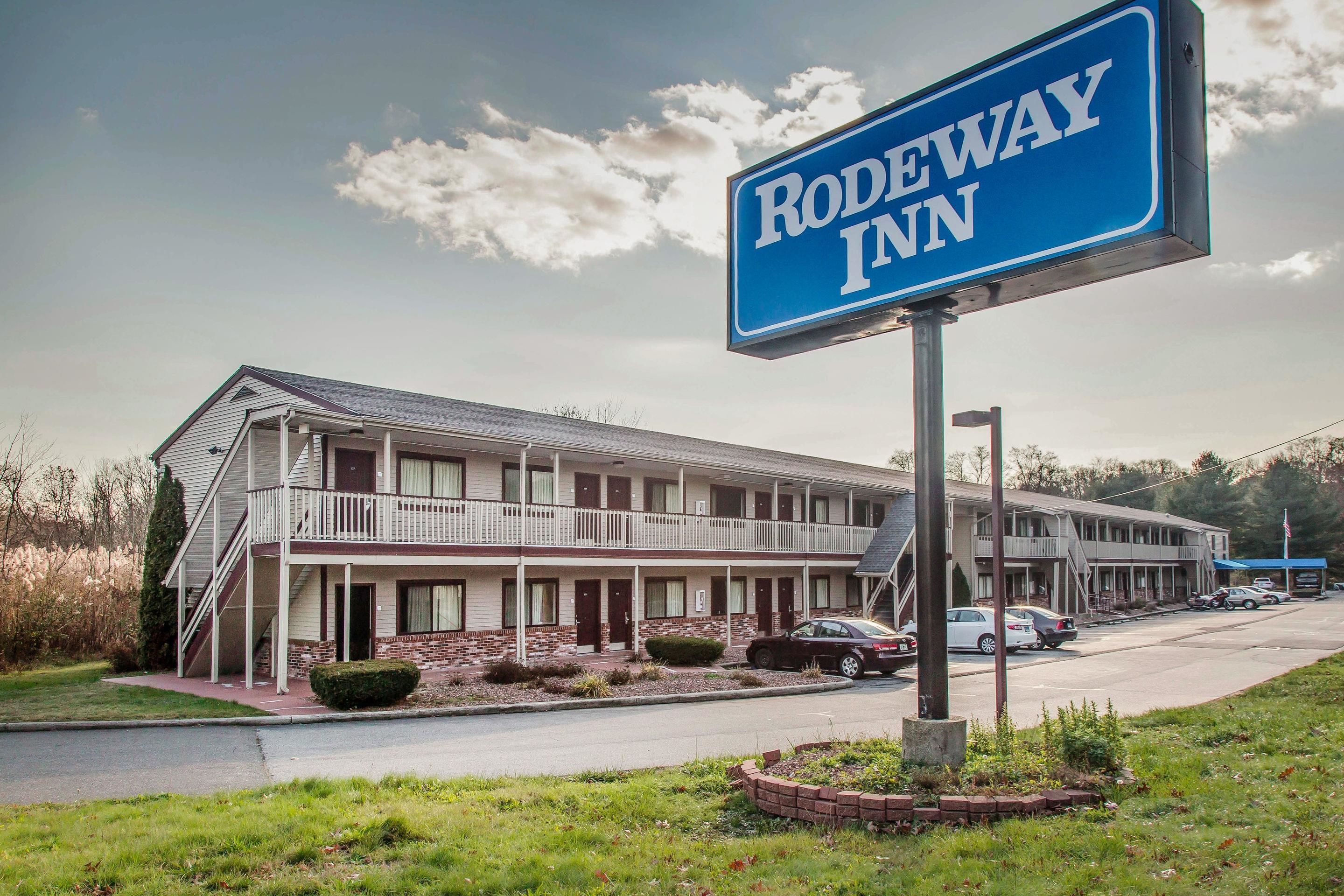 Un motel con un letrero que dice "RODEWAY INN" y un edificio de dos pisos con un balcón en el segundo nivel.