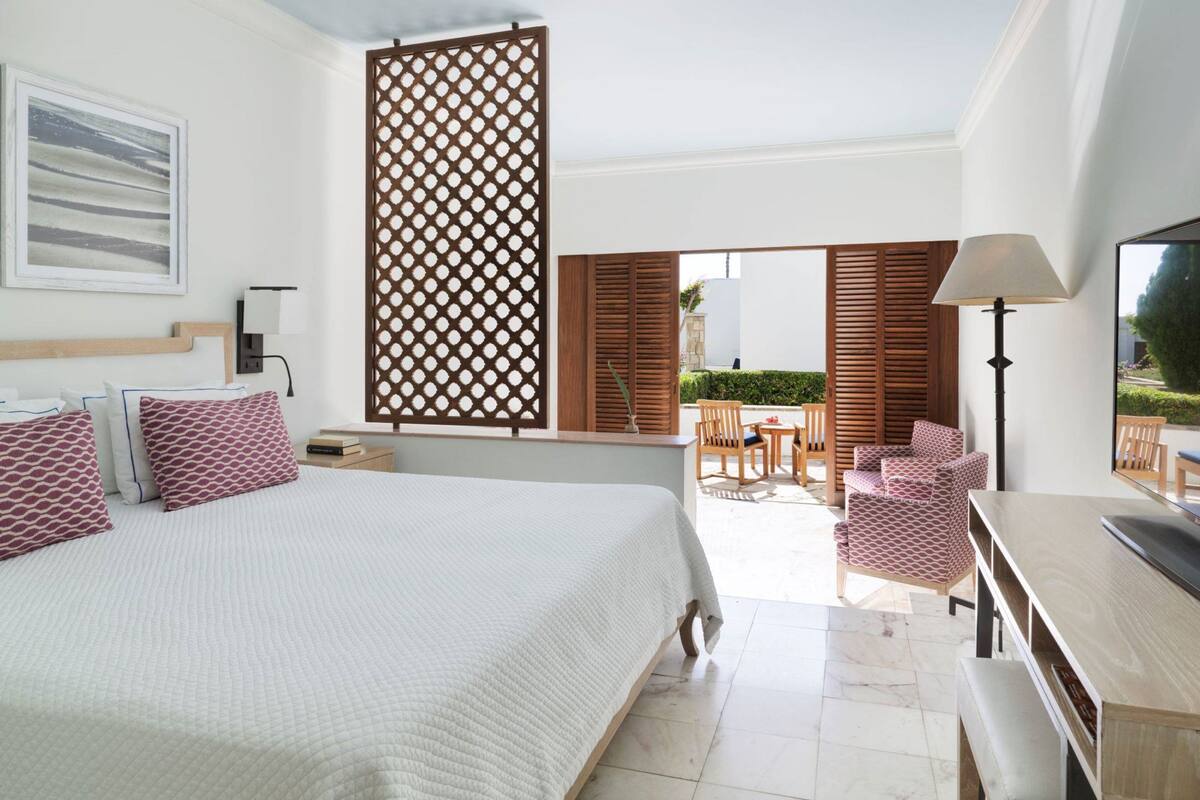 Habitación de hotel con cama, escritorio, silla y vista al patio exterior.