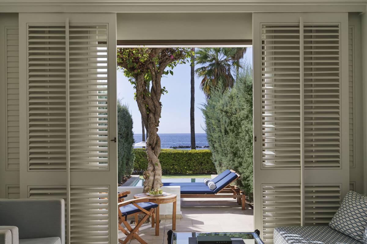 Una habitación con vistas al mar, piscina y mobiliario de exterior.