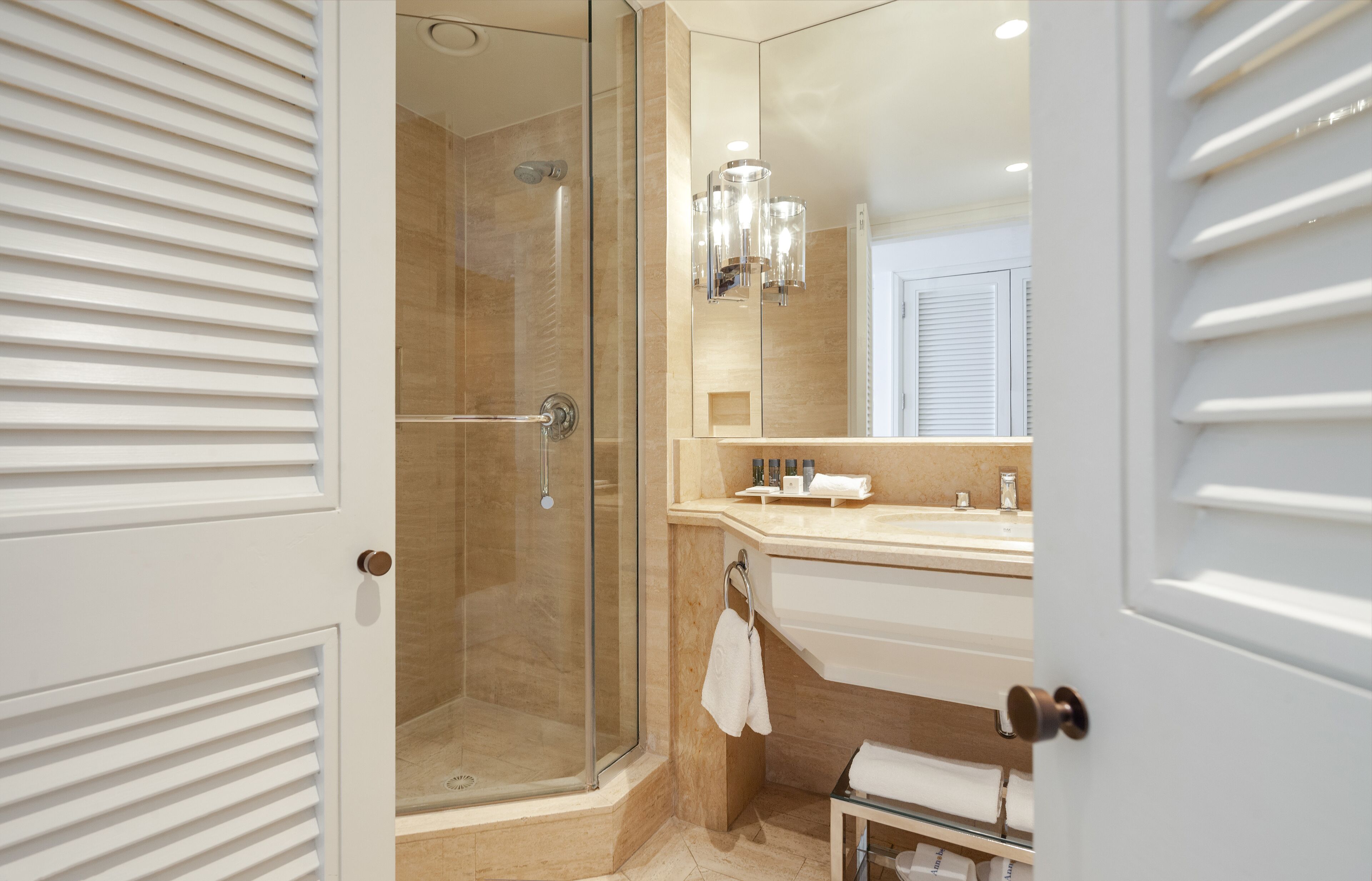 A modern bathroom with a glass-enclosed shower, a large mirror, and a vanity with a sink and towel rack.