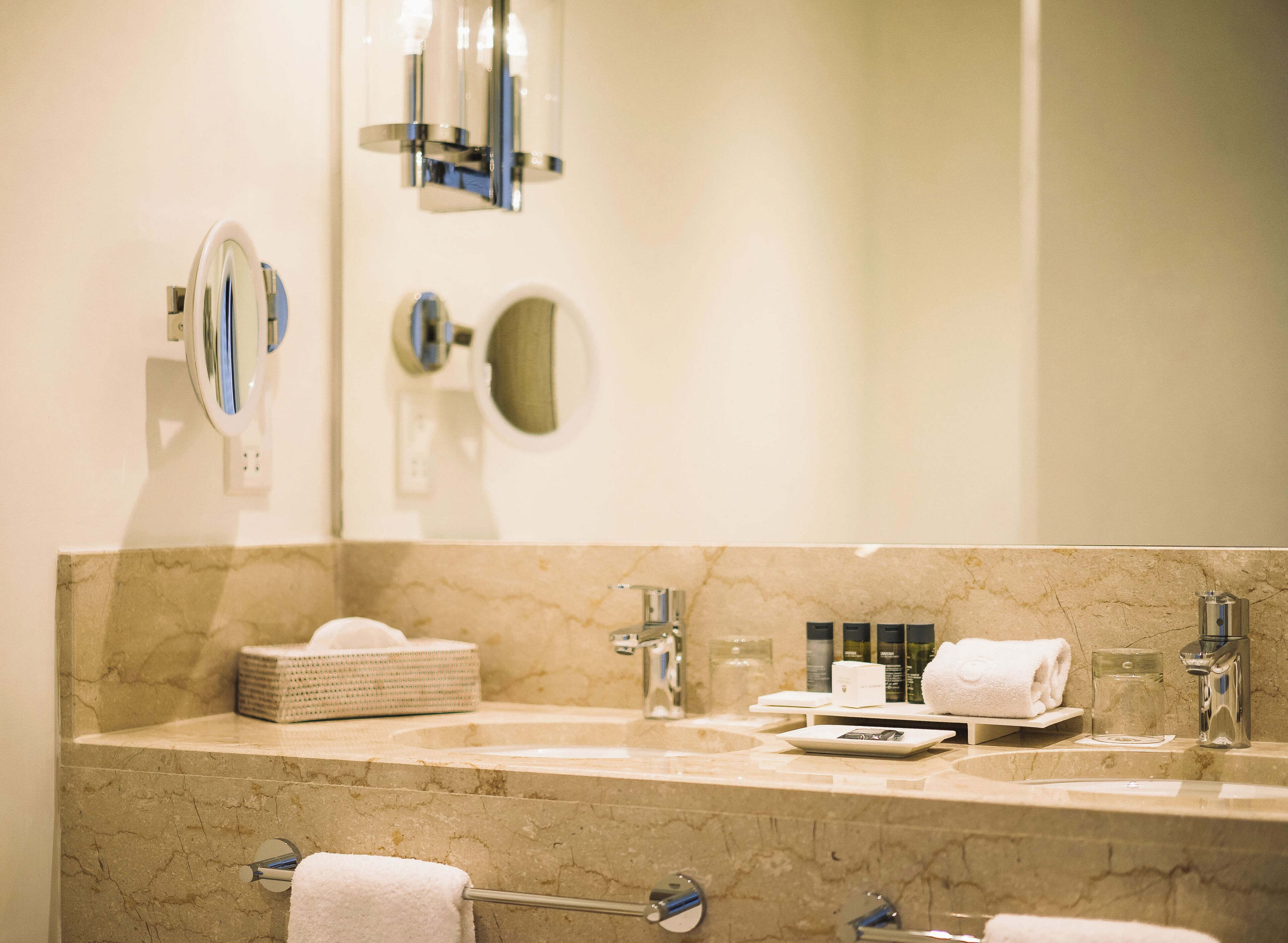 A bathroom with a marble countertop, two sinks, a towel rack, and a mirror.