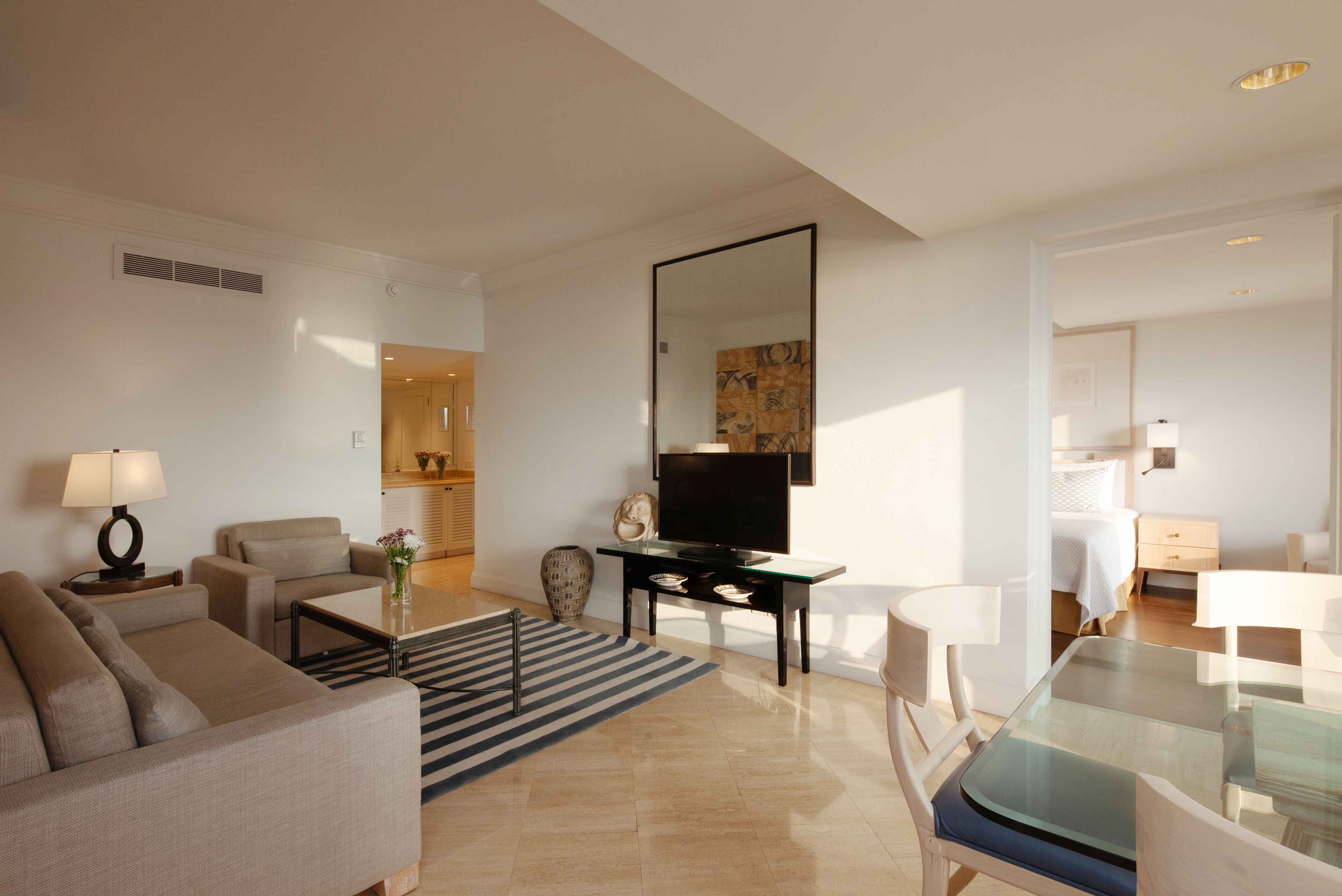 Un salon moderne comprenant un canapé, une table basse, un téléviseur et un coin repas avec une table et des chaises en verre.