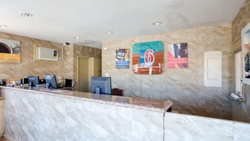 Un espace d’accueil d’hôtel avec des comptoirs en marbre, un ordinateur, un téléphone et une porte.