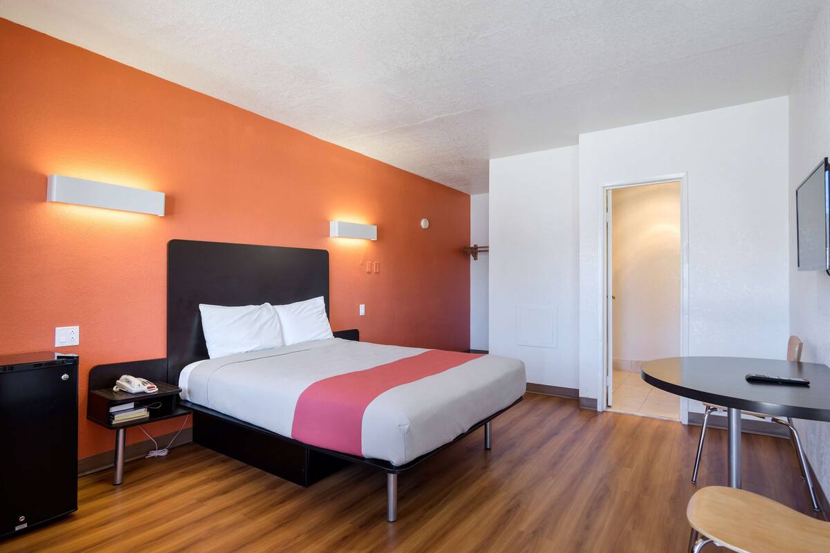 Ein Hotelzimmer mit Bett, Nachttisch, Schreibtisch, Stuhl und Fernseher.