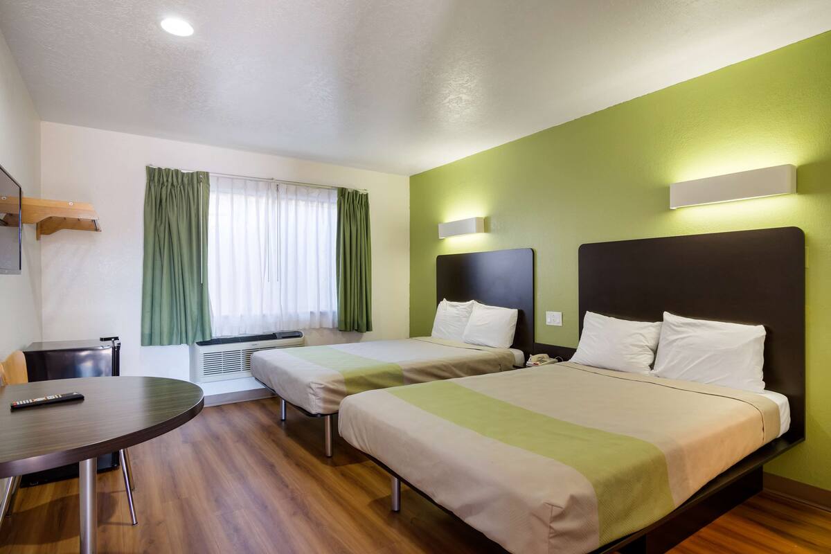 Ein Hotelzimmer mit zwei Betten, einem Schreibtisch und einem Sessel.