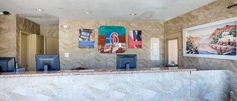 A reception area with marble walls, a reception desk, and a mural.