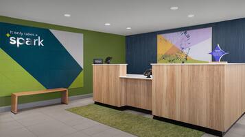 A reception area with a wooden desk, a bench, and a wall with a 'spark' sign.