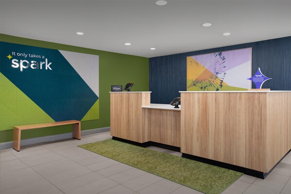 A reception area with a wooden desk, a bench, and a wall with a 'spark' sign.