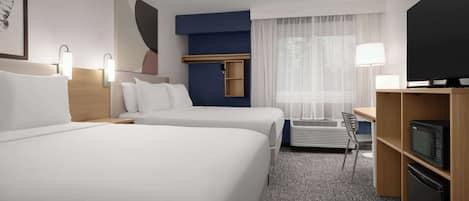 Habitación de hotel con dos camas, un escritorio con silla, televisor y microondas.