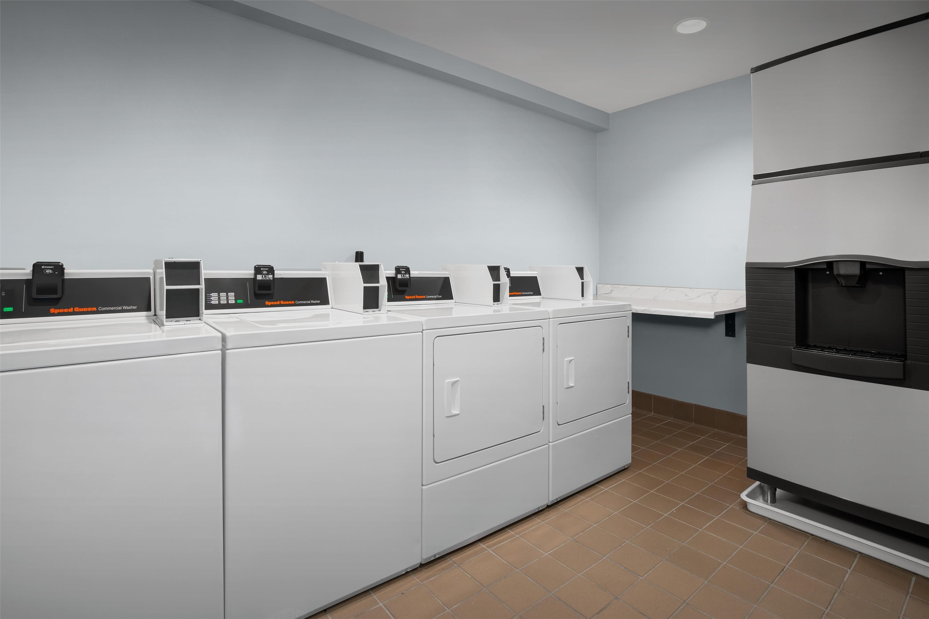 A laundry area with multiple washing machines and a refrigerator.