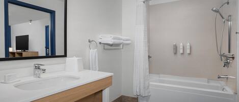 Un baño moderno con un espejo grande, dos lavamanos, una bañera y una ducha.