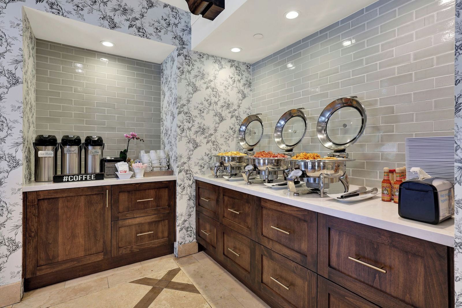 Una cocina con estación de café, un bufé con diversas opciones de comida y un espejo.