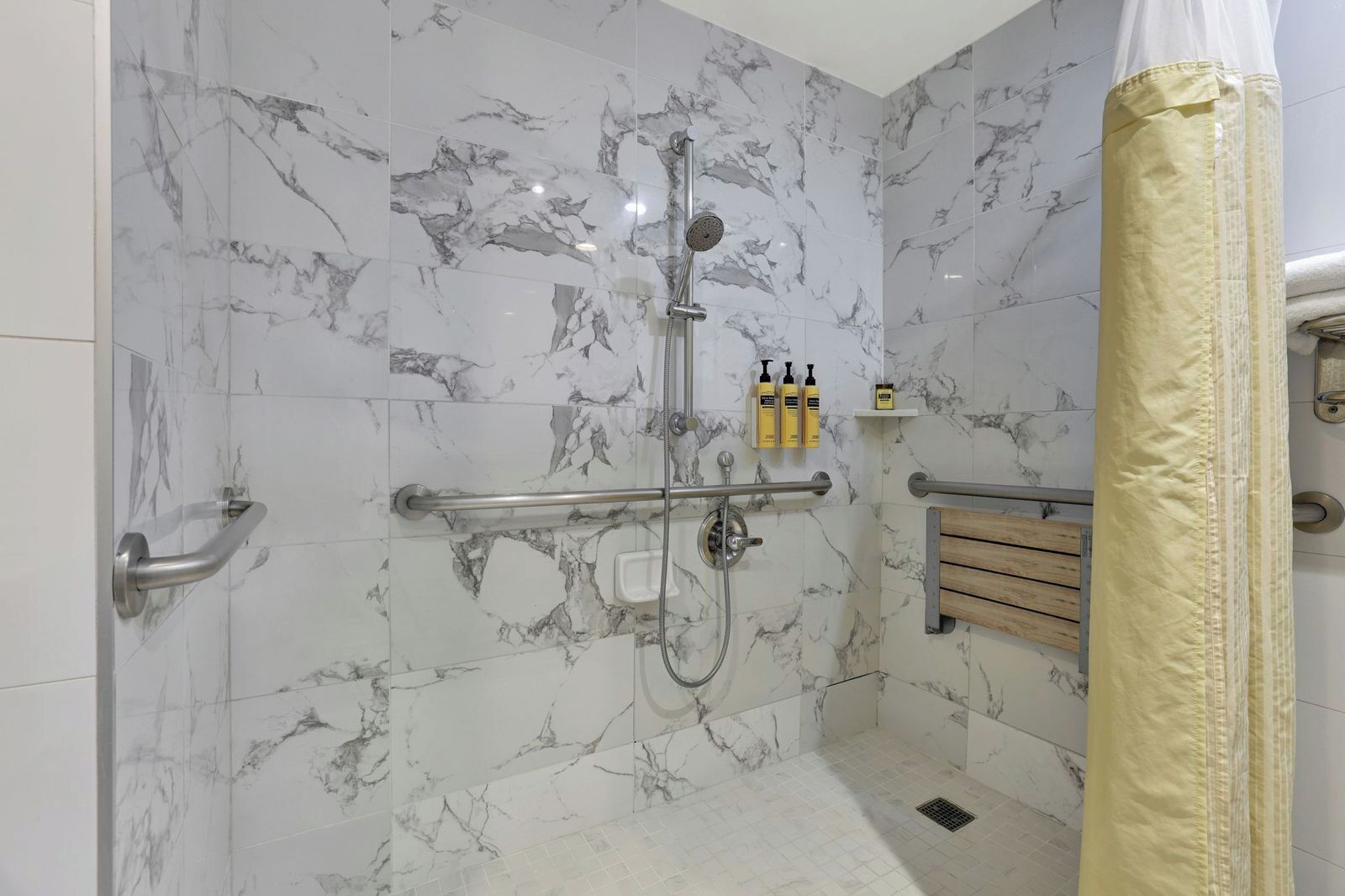 A shower with a handheld showerhead, a handheld showerhead, and a handheld showerhead.