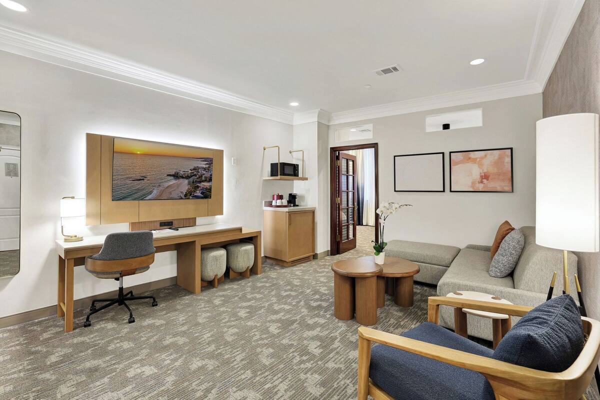 Une chambre d’hôtel équipée d’un bureau, d’une chaise, d’un canapé et d’un téléviseur fixé au mur.