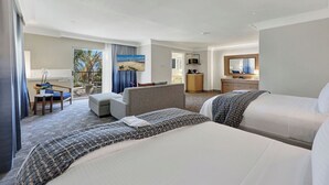 A hotel room with a large bed, a sofa, a desk, and a balcony with a view.