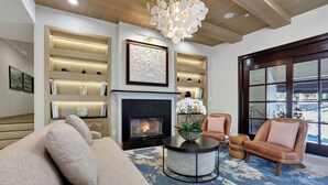 A modern living room with a fireplace, a sofa, a round coffee table, and a large window with a view.