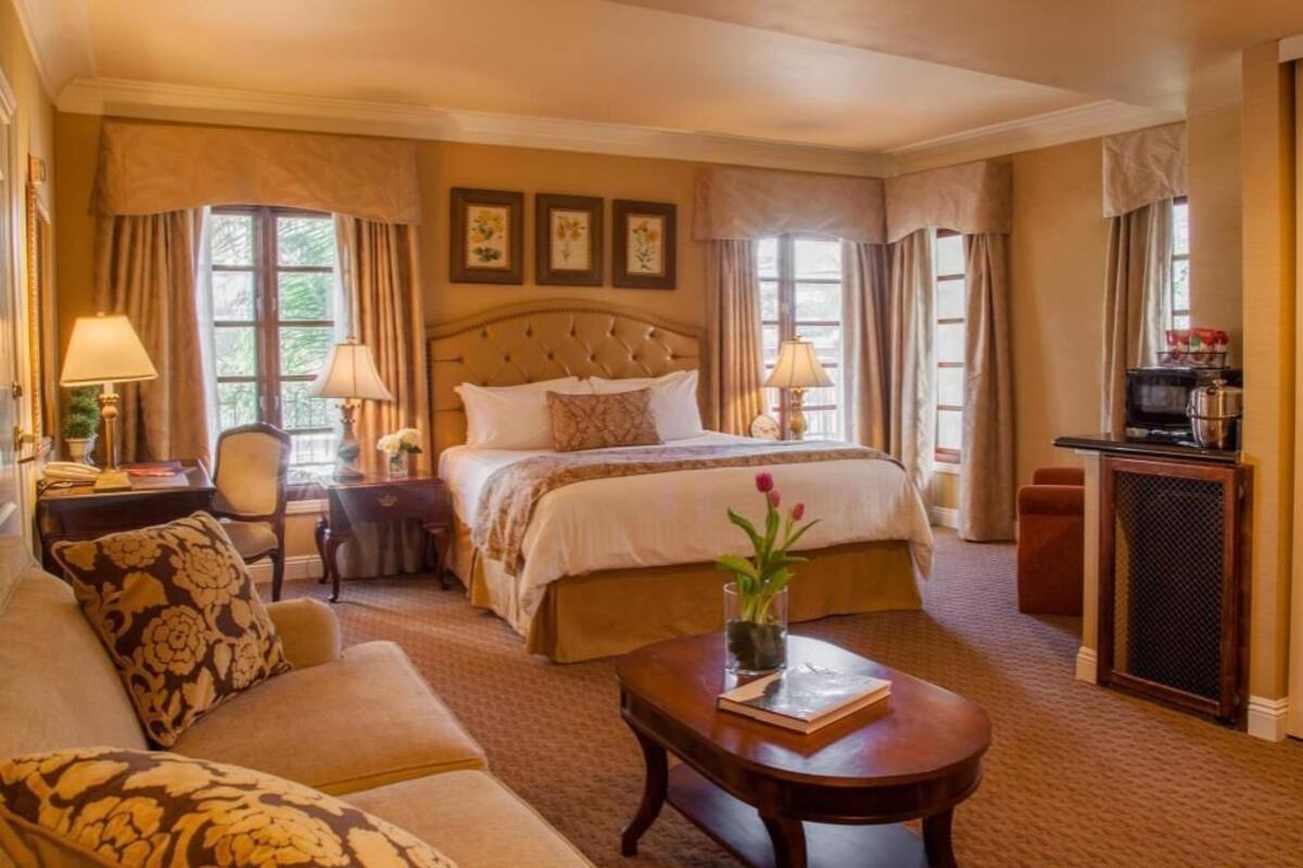 Une chambre d’hôtel avec un grand lit, un canapé, une table basse, un bureau et un téléviseur.