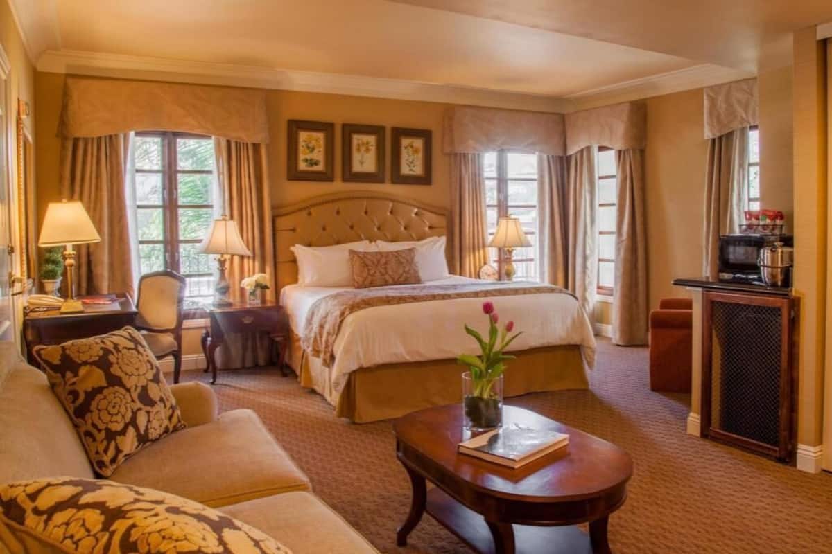 Ein Hotelzimmer mit einem großen Bett, einer Schlafcouch, einem Couchtisch, einem Schreibtisch und einem Fernseher.