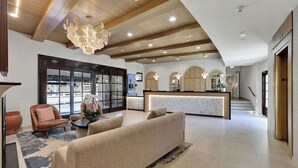 A spacious lobby with a reception desk, seating area, and a staircase leading to upper floors.