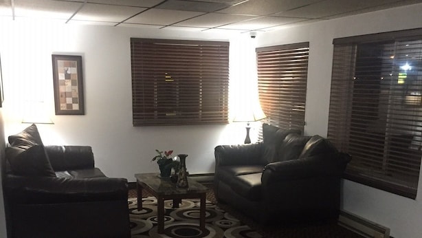 A living room with two leather sofas, a coffee table, and a patterned rug. - Sunset Inn & Suites - Lincoln Airport (Lincoln)