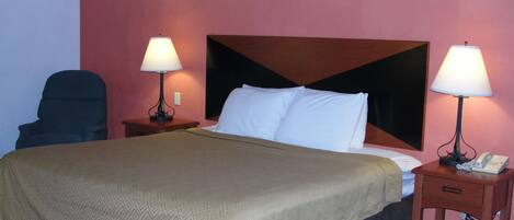 Una habitación de hotel con una cama grande, dos lámparas de noche, un teléfono y una silla.