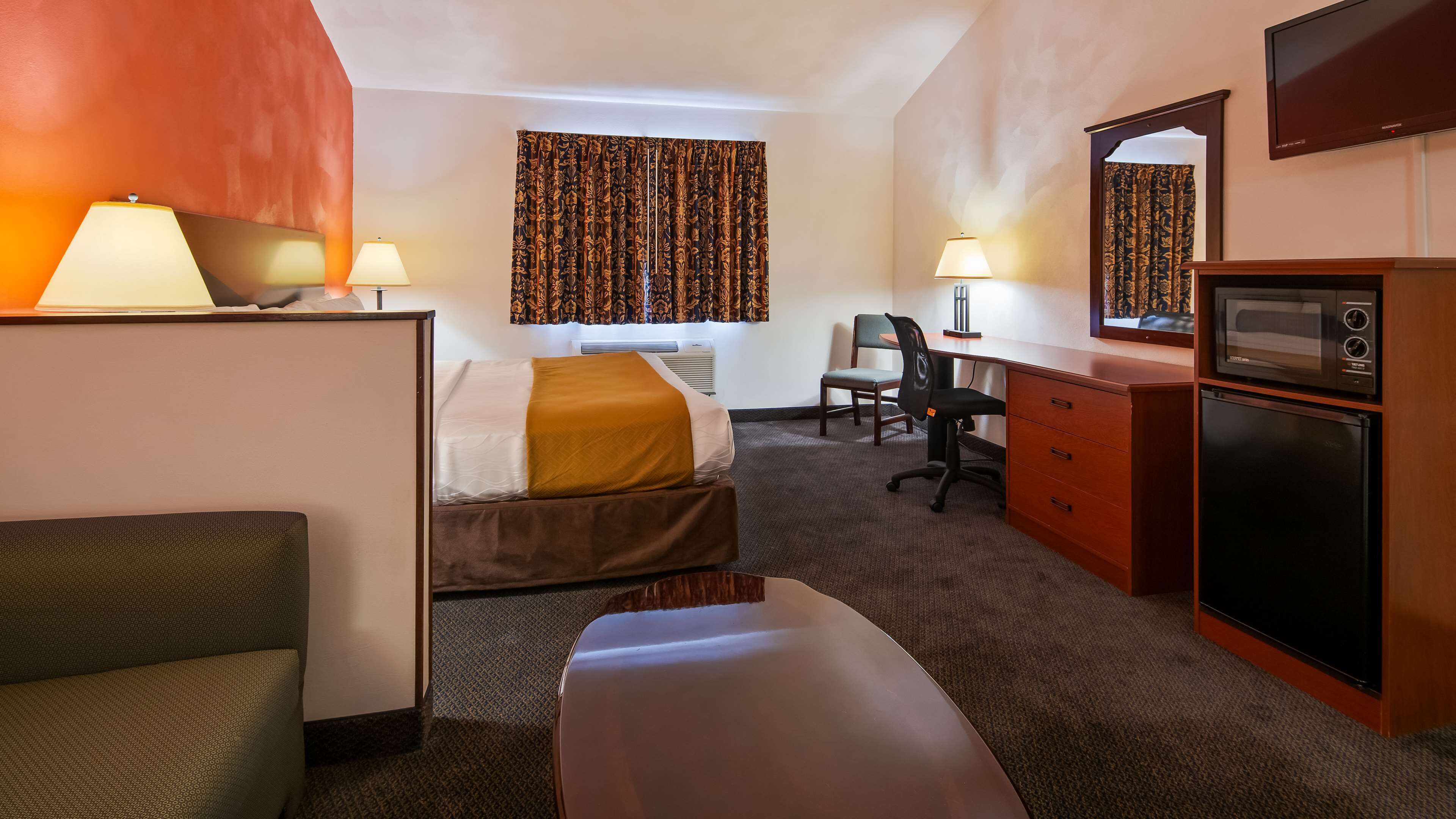 Ein Hotelzimmer mit zwei Betten, einem Schreibtisch, einem Stuhl, einer Mikrowelle und einem Kühlschrank.