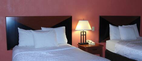 Two single beds with white linens and headboards, a bedside table with a lamp, and a telephone.