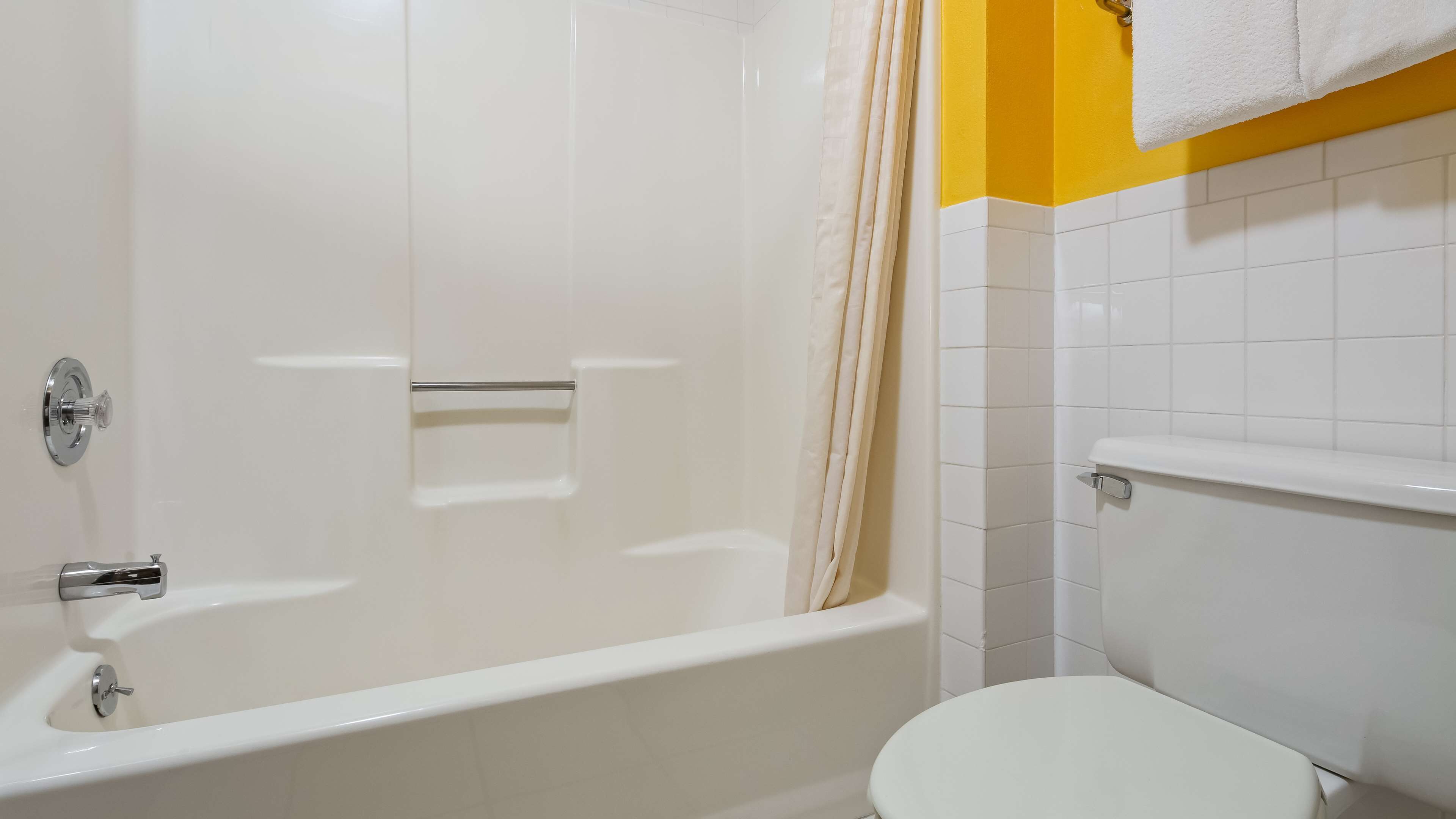 A bathroom with a white bathtub, a toilet, and a shower curtain.