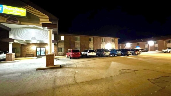 A parking lot with several cars parked in front of a building with a 'SureStay' sign.