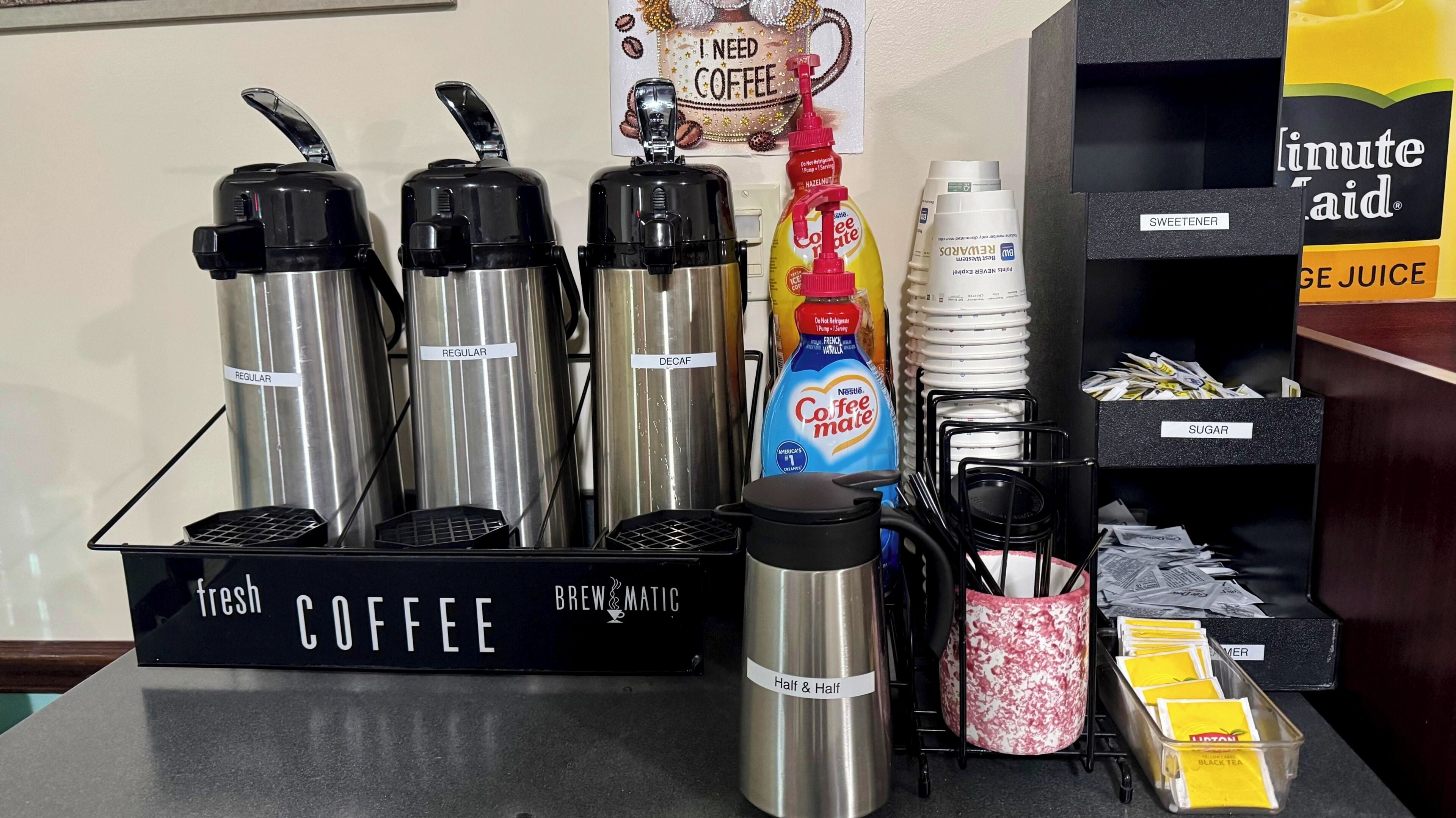 A coffee station with labeled thermos cups, a coffee machine, a mug, and various coffee-related products.