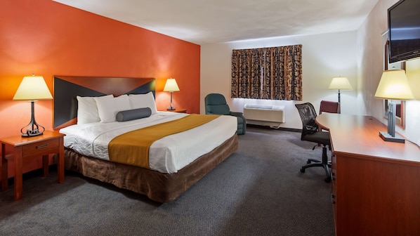 A hotel room with a large bed, two bedside tables with lamps, a desk with a chair, and a TV.