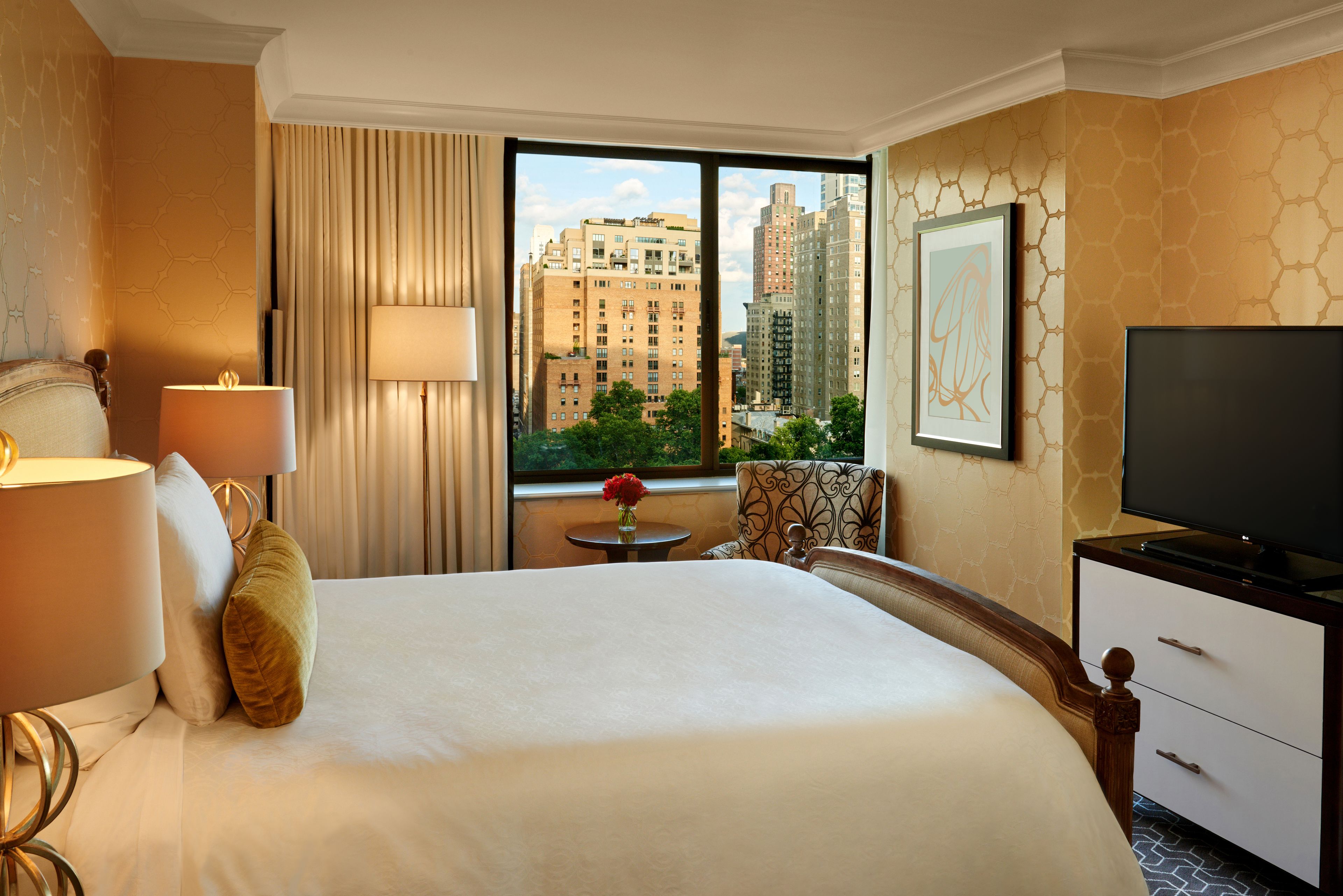 Une chambre d’hôtel avec un grand lit, une télévision, un bureau et une fenêtre donnant sur la ville.