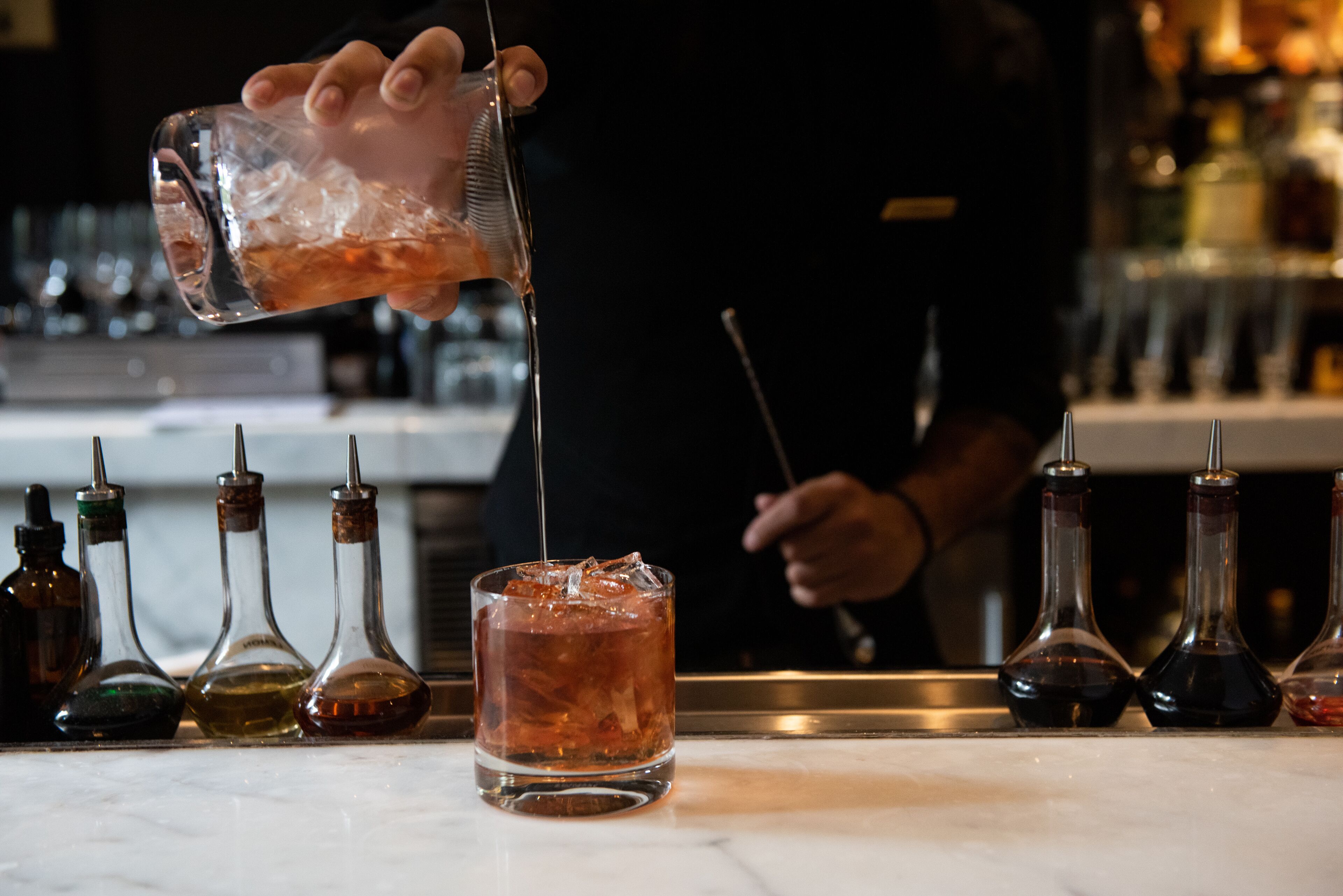 Um bartender servindo uma bebida em um copo.