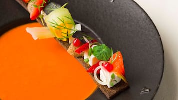 A dish with various toppings on a slice of bread, accompanied by a side of orange sauce.