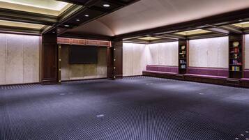 A conference room with a large screen, wooden paneling, and a carpeted floor.